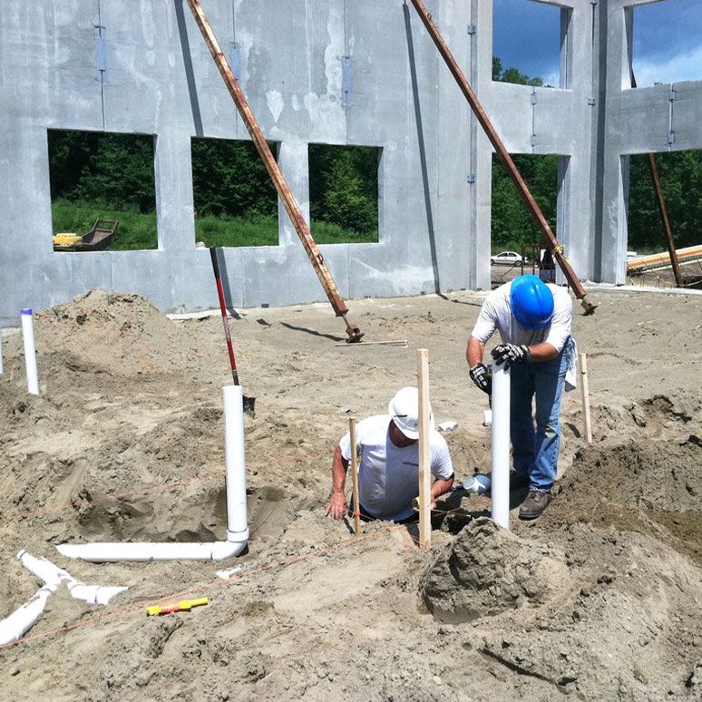 Installing underground plumbing at building construction site